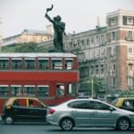Urban scene featuring a classic red double-decker bus and historic architecture, typical of Mumbai's vibrant streets.