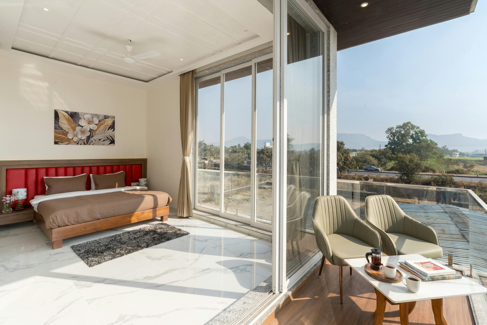 Spacious modern bedroom with large windows offering a scenic view and elegant interior design.