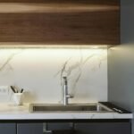 A stylish modern kitchen featuring a sleek faucet, marble surfaces, and minimalist design.