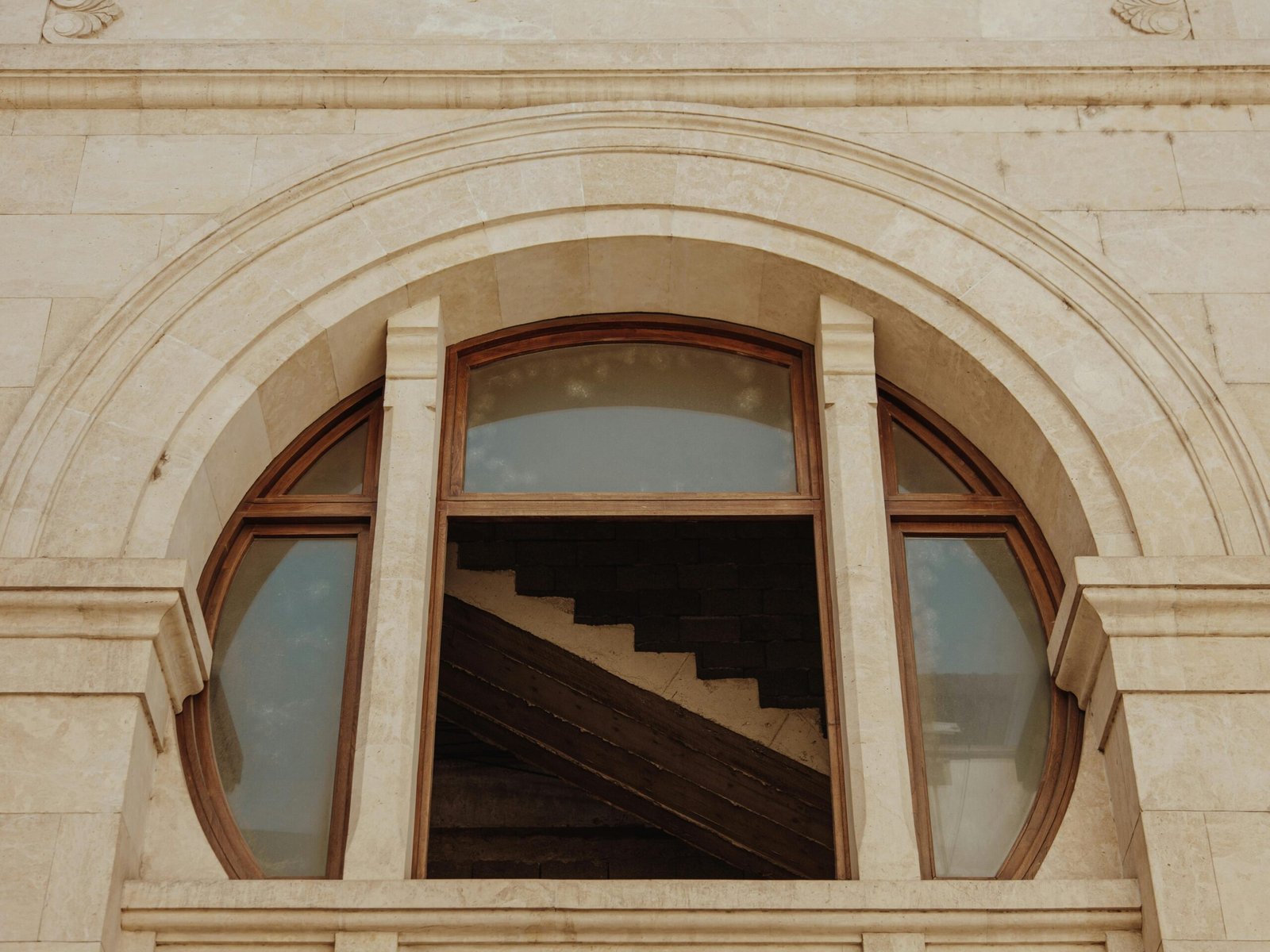 Detailed view of a stone arch with wooden framed windows visible in daylight.