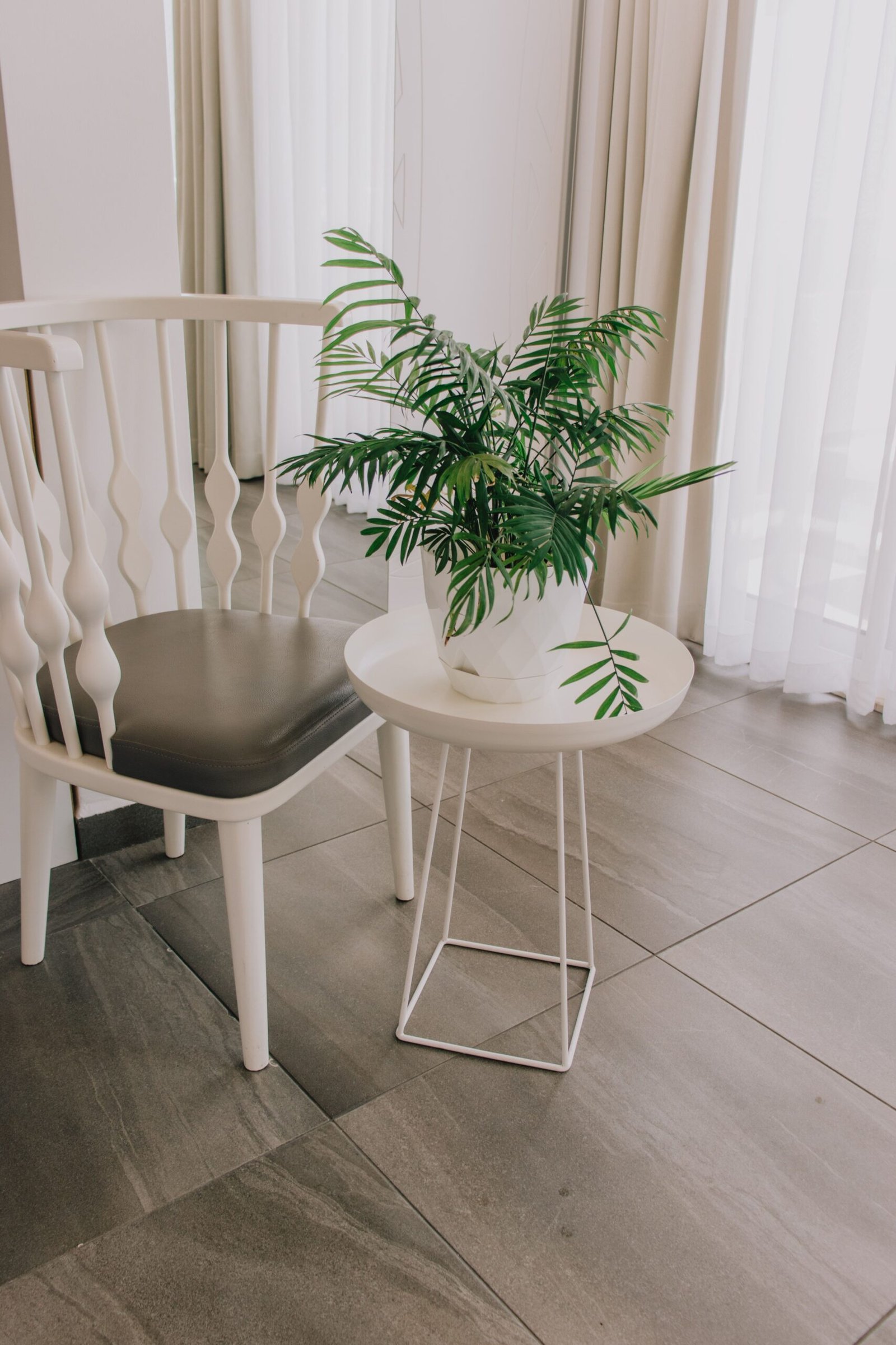A sleek modern interior featuring a white chair and a potted plant on a small table.