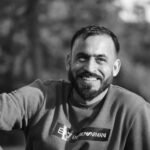 Black and white portrait of a smiling man outdoors, showcasing a relaxed and happy mood.