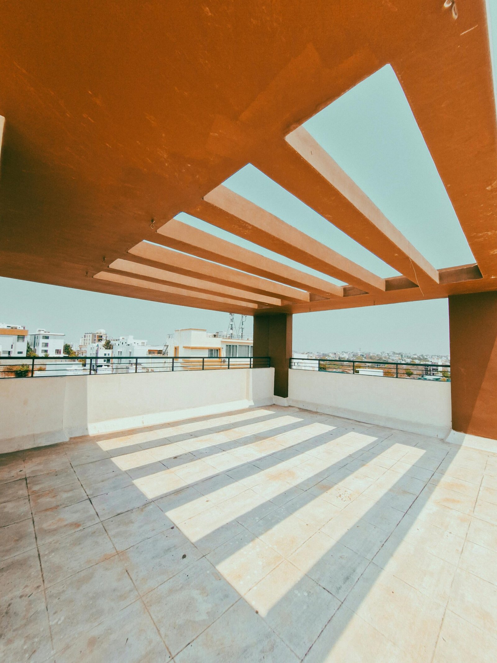 Bright and spacious rooftop terrace featuring a striking geometric canopy and clear sky view.
