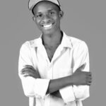 Casual portrait of a smiling man wearing a white shirt and a cap in black and white.
