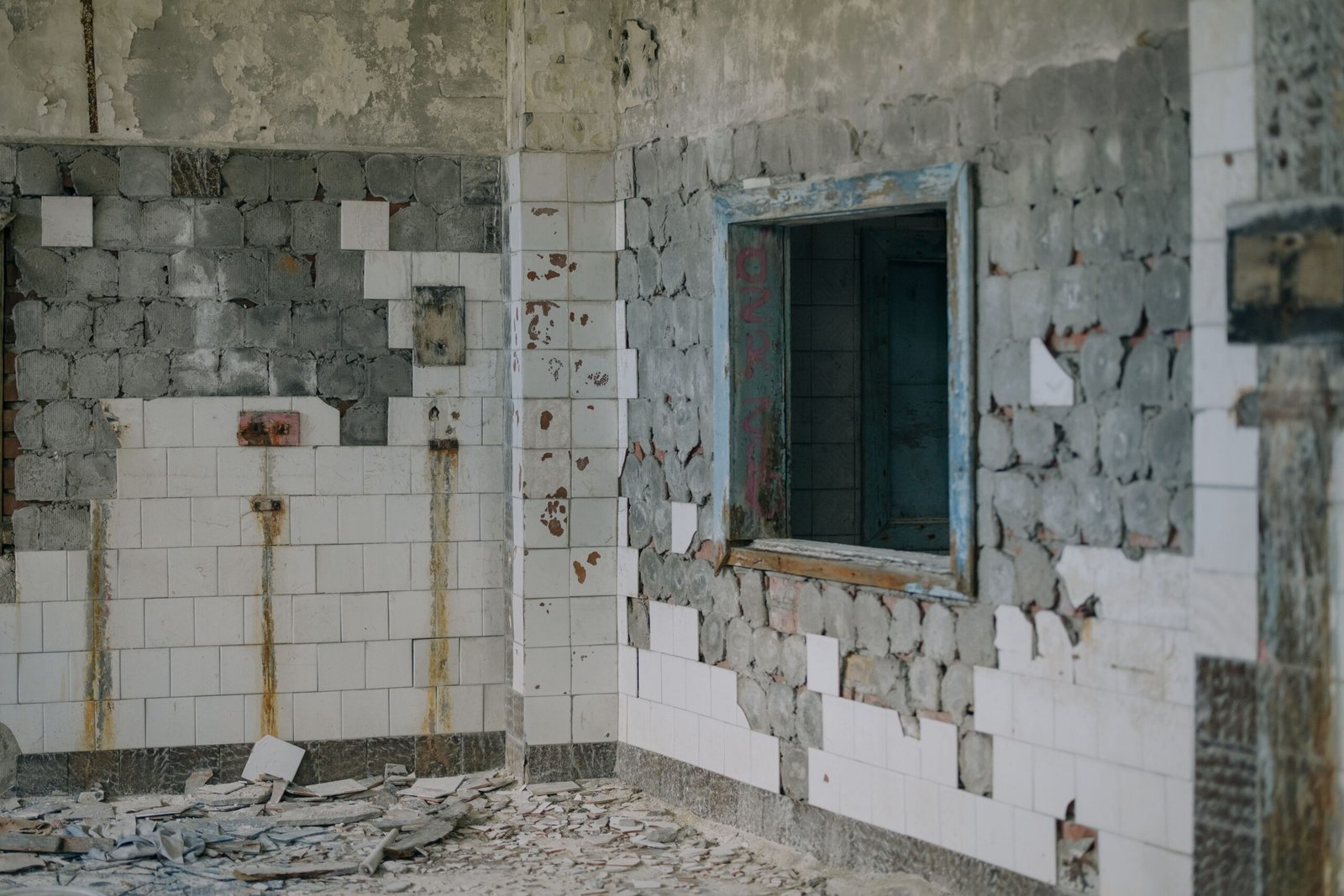 A decayed interior of a building with exposed bricks and tiles, suggesting abandonment.