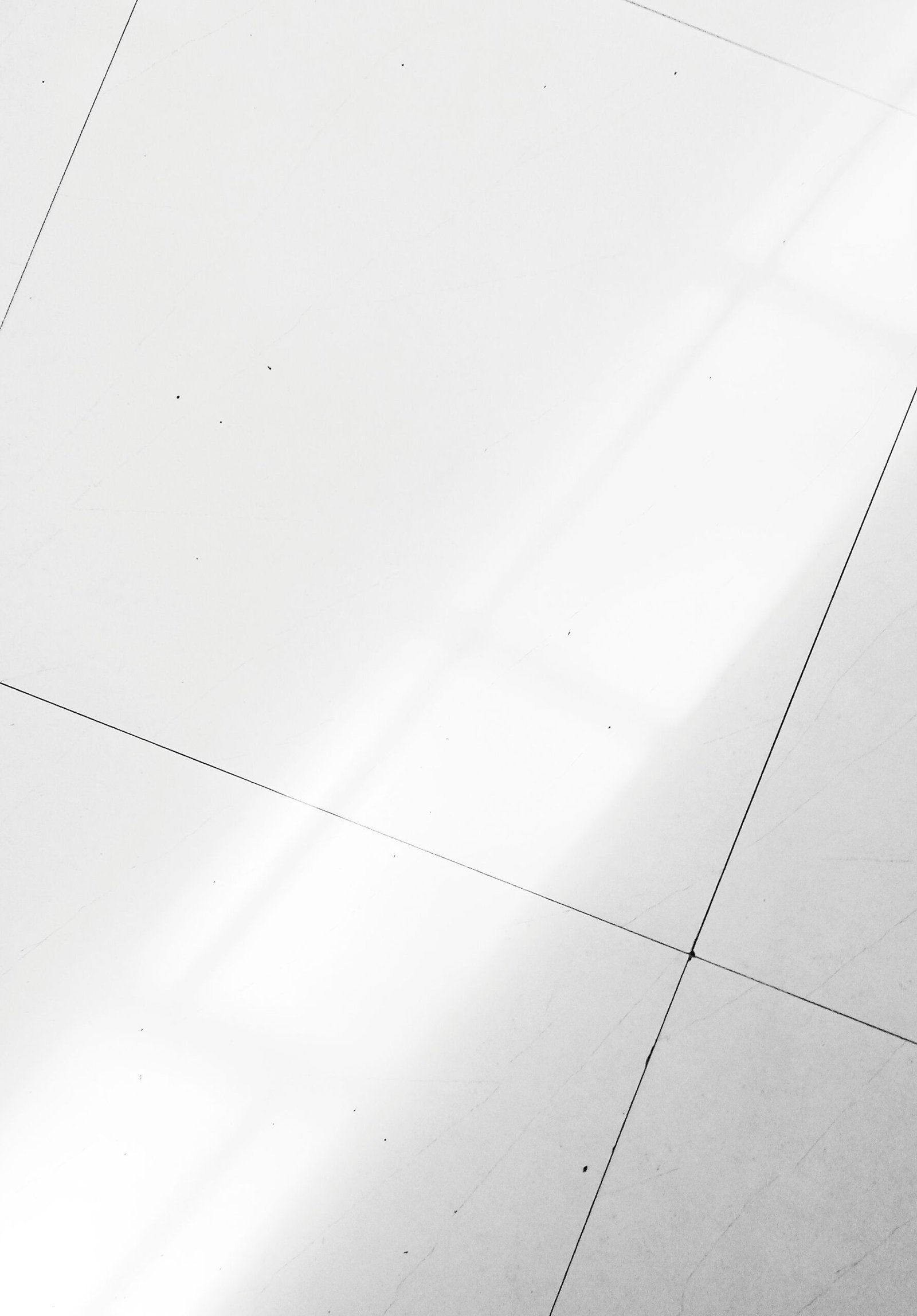 From above background of white clean floor with tiles of modern light room in apartment with bright sunlight in sunny weather